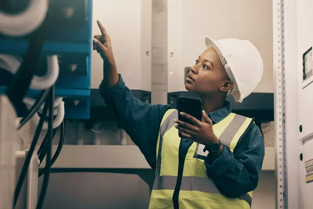 Black woman, engineering technician and phone in control room to connect system, mechanic industry